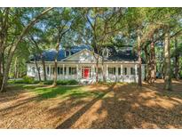 Charming home featuring a red front door and a welcoming porch with white columns, nestled among mature trees at 4000 Rouse Rd, Orlando, FL 32817