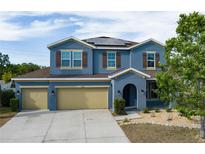 Charming two-story home with blue exterior, brown shutters, three-car garage, and solar panels at 4058 Brookshire Cir, Eustis, FL 32736