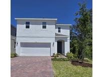 Charming two-story home with a red brick driveway, a two-car garage, and a well-manicured lawn at 1096 Happy Forest Loop, Deland, FL 32720