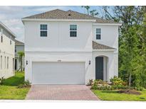 Charming two-story home featuring a two-car garage, brick driveway, and neatly landscaped front yard at 1096 Happy Forest Loop, Deland, FL 32720
