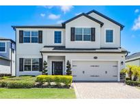 Charming two-story home features a two-car garage, dark shutters, and manicured landscaping at 13320 Magnolia Valley Dr, Clermont, FL 34711