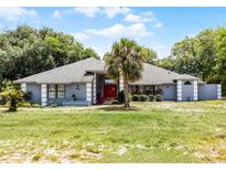 Charming single-story home with a well-manicured lawn and a vibrant red front door at 1689 Saboff Way, Chuluota, FL 32766