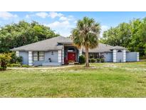 Charming single-story home with a well-manicured lawn, palm tree, and inviting red front door at 1689 Saboff Way, Chuluota, FL 32766