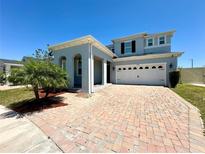 Charming two-story home features a brick driveway and attached two-car garage under a clear blue sky at 2648 Needlepoint St, Kissimmee, FL 34741