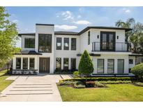 Stunning two-story modern home with a clean white facade, balcony, and professionally landscaped front yard at 1700 Palm Ave, Winter Park, FL 32789