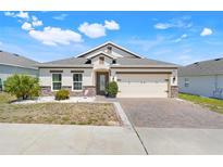 Charming single-story home featuring a brick-paved driveway, two-car garage, and well-maintained landscaping at 210 Hydra Way, Groveland, FL 34736