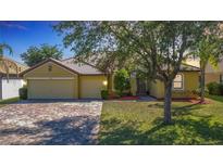 Inviting single-story home with a well-manicured lawn, brick driveway, and a two-car garage at 3908 Coastal Breeze Dr, Kissimmee, FL 34744