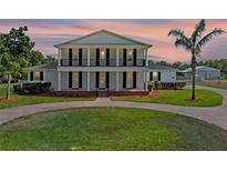Stunning two-story home with a beautiful lawn and a circular driveway framed by classic columns and a balcony at 4232 Spring Ln, Lakeland, FL 33811