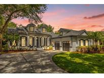 Stunning exterior of a home with a long drive, a three-car garage, and manicured landscaping at 8440 Woburn Ct, Windermere, FL 34786