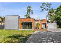 Modern home featuring wood and metal siding with manicured lawn and concrete driveway on a sunny day at 11734 Lake Willis Dr, Orlando, FL 32821