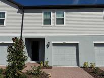 Charming townhome showcasing gray siding, a brick walkway, and a single-car garage at 16464 Happy Eagle Dr, Clermont, FL 34714