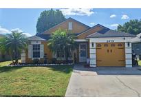 Charming single-story home with a manicured lawn, palm trees, and a two-car garage at 2979 Cool Breeze Cir, St Cloud, FL 34769
