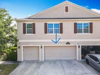 Two-story townhouse showcasing a multi-car garage, and neutral-colored exterior with well-placed windows and brown shutters at 3449 Seneca Club Loop # B, Orlando, FL 32808