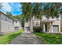 Charming townhomes featuring lush landscaping, a brick driveway, and attached garages at 41 E Spruce St, Orlando, FL 32804