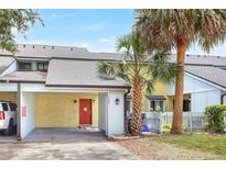 Charming townhome featuring a vibrant red front door, carport, and mature palm trees enhancing curb appeal at 7484 Canford Ct # 8, Winter Park, FL 32792
