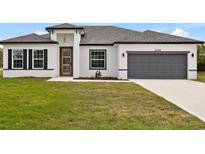 Charming single-story home featuring a gray two-car garage and a well-manicured lawn under a bright blue sky at 15046 Sw 48Th Ave, Ocala, FL 34473