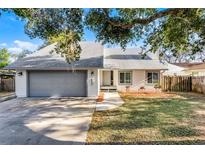 Charming one-story home with a gray roof, a gray garage door, and mature trees at 1220 Rolling Ln, Casselberry, FL 32707