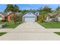 Charming blue home with a well-maintained lawn and a long driveway leading to an attached two-car garage at 212 Hound Run Pl, Casselberry, FL 32707