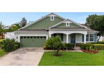 Charming single-story home featuring a well-manicured lawn, lush landscaping, and a welcoming front porch at 690 Cascading Creek Ln, Winter Garden, FL 34787