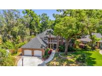 Aerial view of a brick home with three-car garage, driveway, and surrounded by lush greenery and trees at 950 Deerwood Loop, Longwood, FL 32779