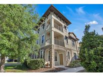 Beautiful three-story townhome with stone accents and dual balconies, enhanced by lush landscaping at 1339 Shinnecock Hills Dr, Davenport, FL 33896