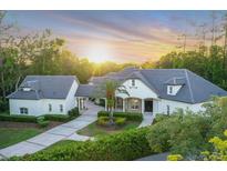 Stunning single-story home featuring lush landscaping, porte cochere, and a paver driveway at sunset at 1906 Oakbrook Dr, Longwood, FL 32779