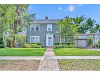 Charming two-story home featuring a well-manicured lawn, brick walkway, and a welcoming light blue front door at 216 E Vanderbilt St, Orlando, FL 32804