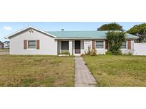 Charming single-story home featuring a green roof, manicured lawn, and decorative shutters at 2314 Meadowbrook St, Kissimmee, FL 34744