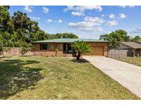 Charming brick home featuring an attached garage, green roof, and a well-manicured lawn in a desirable neighborhood at 255 Katrina St, De Leon Springs, FL 32130