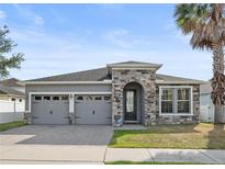 Charming single-story home featuring a stone-accented entrance, gray stucco, and a well-manicured lawn at 5108 Creekside Park Ave, Orlando, FL 32811