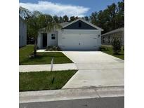Charming single-story home featuring a two-car garage and a well-maintained front yard with green grass at 976 Commons Way, Port Orange, FL 32129