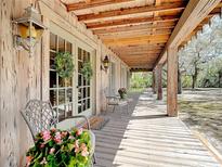 Charming covered porch featuring comfortable seating and decorative wreaths on glass paneled doors at 3939 Lake Erie Rd, Groveland, FL 34736