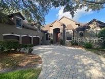Elegant home with a paver driveway, three-car garage, and beautiful landscaping at 708 Palenci Ct, Winter Springs, FL 32708