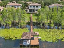 Stunning aerial view of a waterfront estate with a private dock and boat lift on a serene lake at 7624 Pointe Venezia Dr, Orlando, FL 32836