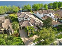 Aerial view of a home with a terracotta tile roof, lush landscaping, and a glimpse of the adjacent lake at 7624 Pointe Venezia Dr, Orlando, FL 32836