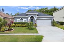 Charming single-story home featuring a manicured lawn, arched entryway, and a two-car garage at 826 Jade Forest Ave, Orlando, FL 32828