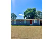 Charming single-story home featuring a well-manicured lawn and a vibrant red front door at 9400 Se 119Th St, Belleview, FL 34420