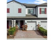 Charming townhome featuring a brick driveway, attached garage, well-maintained landscaping, and neutral-toned exterior at 308 Rustic Loop, Sanford, FL 32771