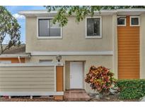 Two-story townhome featuring a white door, beige stucco and orange wood facade, and a well-kept yard at 66 Silver Falls Cir, Kissimmee, FL 34743