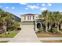 Inviting two-story home featuring a well-manicured lawn, mature palm trees and a neutral color palette at 5270 Wildwood Way, Davenport, FL 33837