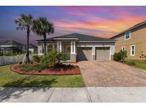 Inviting single-story home featuring a two-car garage, brick paver driveway, and lush landscaping at 8058 Corkfield Ave, Orlando, FL 32832