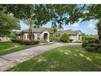 Charming single-story home boasting lush landscaping, a concrete driveway, and a well-maintained green roof at 9138 Pinnacle Cir, Windermere, FL 34786