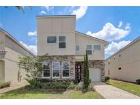Modern two-story home with stone accents, manicured landscaping, and a charming front entrance at 2009 Tropical Palms Cir, Kissimmee, FL 34747