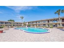 Community pool surrounded by brick pavers and lounge chairs in a well-maintained community on a sunny day at 5505 Hernandes Dr # 204, Orlando, FL 32808