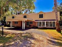 Two-story home with a carport and brick accents, complemented by a well-maintained gravel driveway and verdant surroundings at 76 Oakdale St, Windermere, FL 34786