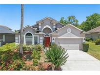 Charming single-Gathering home featuring a well-maintained lawn, flowering plants, and a red front door at 9915 Kona Isle Ct, Orlando, FL 32817