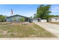 Charming single-story home with blue siding, brick accents, an American flag, and an attached two-car garage at 1328 Laurel Dr, Daytona Beach, FL 32117