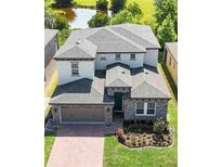 A stunning aerial view of a two-story home showcasing its landscaped yard, covered entryway, and proximity to a pond at 1539 Wynell St, St Cloud, FL 34771