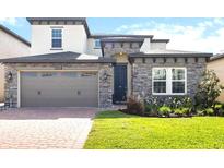 Charming two-story home featuring stone accents, a well-manicured lawn, and a brick driveway at 1539 Wynell St, St Cloud, FL 34771