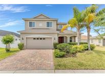 Charming two-story home with manicured landscaping, brick driveway, and a two-car garage at 16078 St Clair St, Clermont, FL 34714